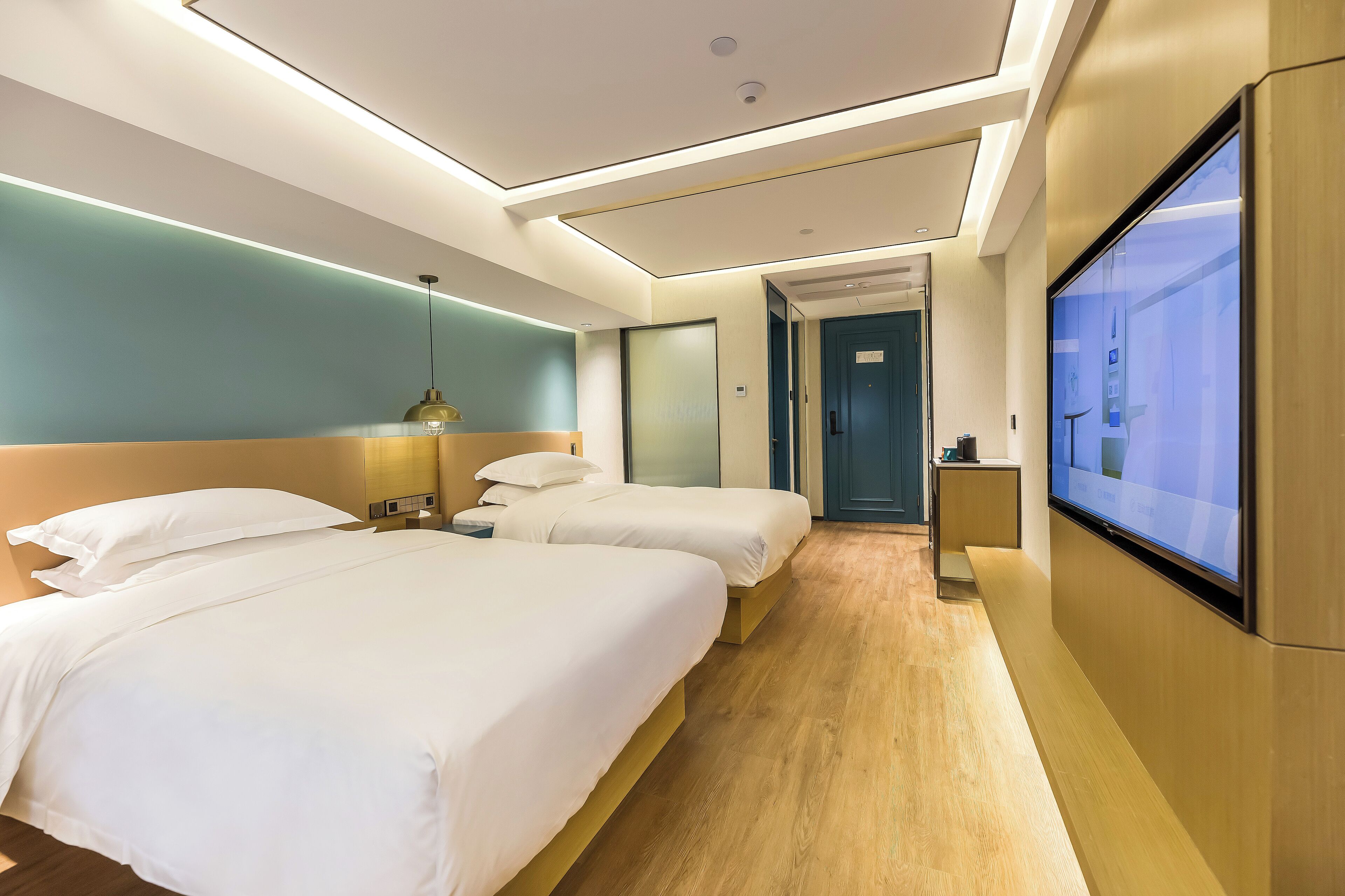 A hotel room with two beds, a TV, and a desk.