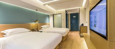 A hotel room with two beds, a TV, and a desk.