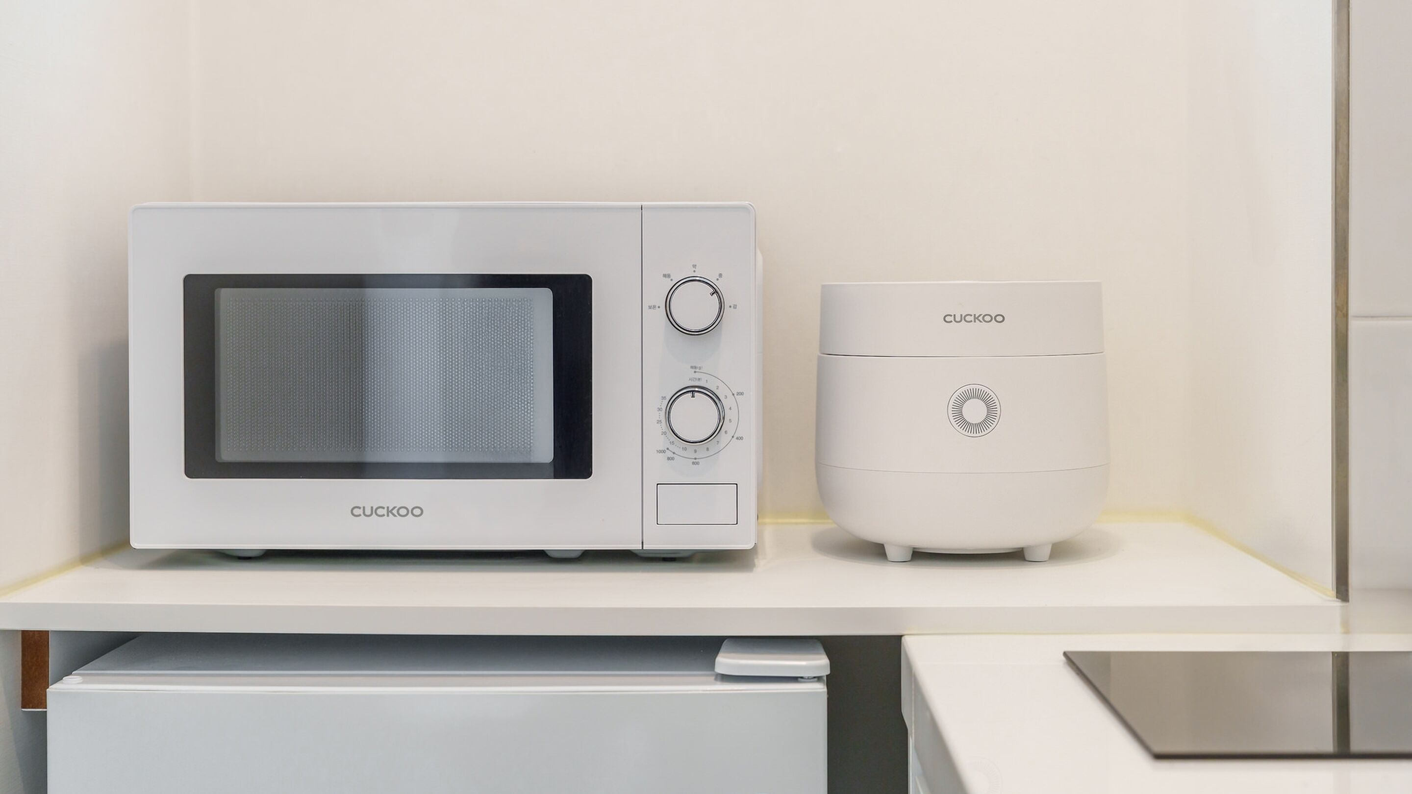 A modern kitchen with a built-in microwave and a compact refrigerator.