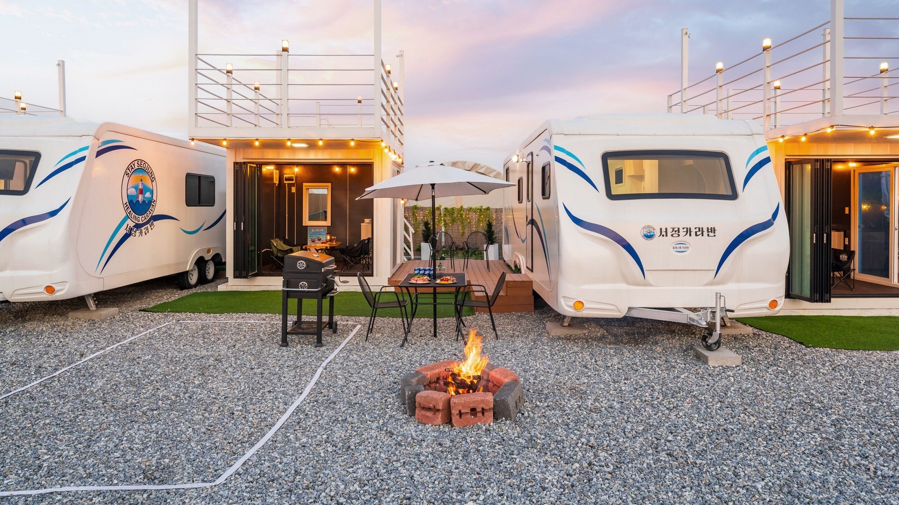 A caravan with a barbecue setup and outdoor seating.