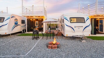 A caravan with a barbecue setup and outdoor seating.