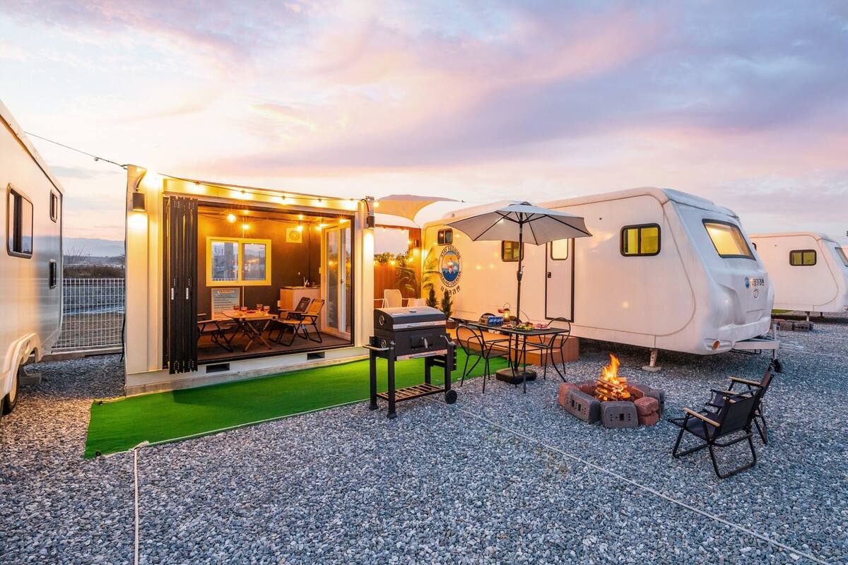 Un hébergement de type caravane avec espace repas extérieur et coin barbecue.