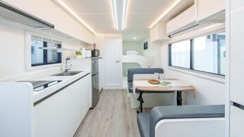 Cocina compacta con microondas, pileta y cocina. Cuenta con un pequeño comedor con mesa y sillas.
