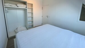 A bedroom with a bed, a wardrobe, and a door.