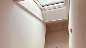 A staircase with wooden steps leading upwards, a skylight at the top, and a smoke detector on the wall.