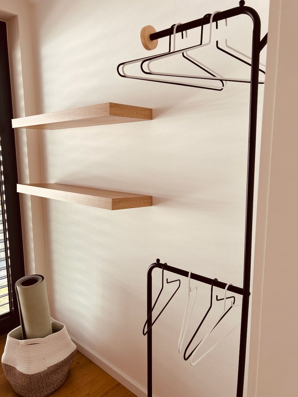 Ein an der Wand befestigter Wäschetrockner mit Holzböden und Metallkleiderbügeln.