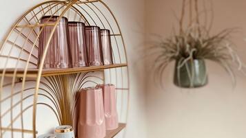Une étagère murale agrémentée d’objets décoratifs et d’une plante suspendue.