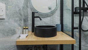 A modern bathroom with a round black sink on a wooden countertop, a mirror, and a glass shower enclosure. - Magnificent Studio - 4P- Sacre-coeur (Paris)