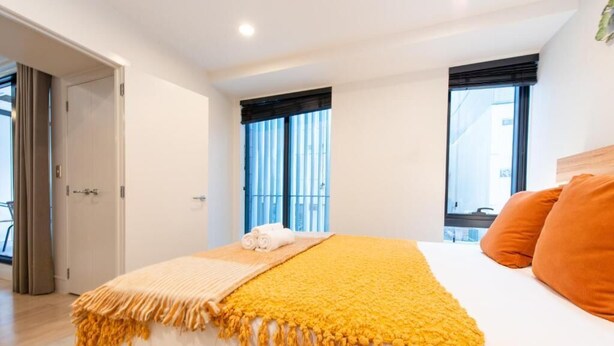 A bedroom with a bed, a window, and a door.