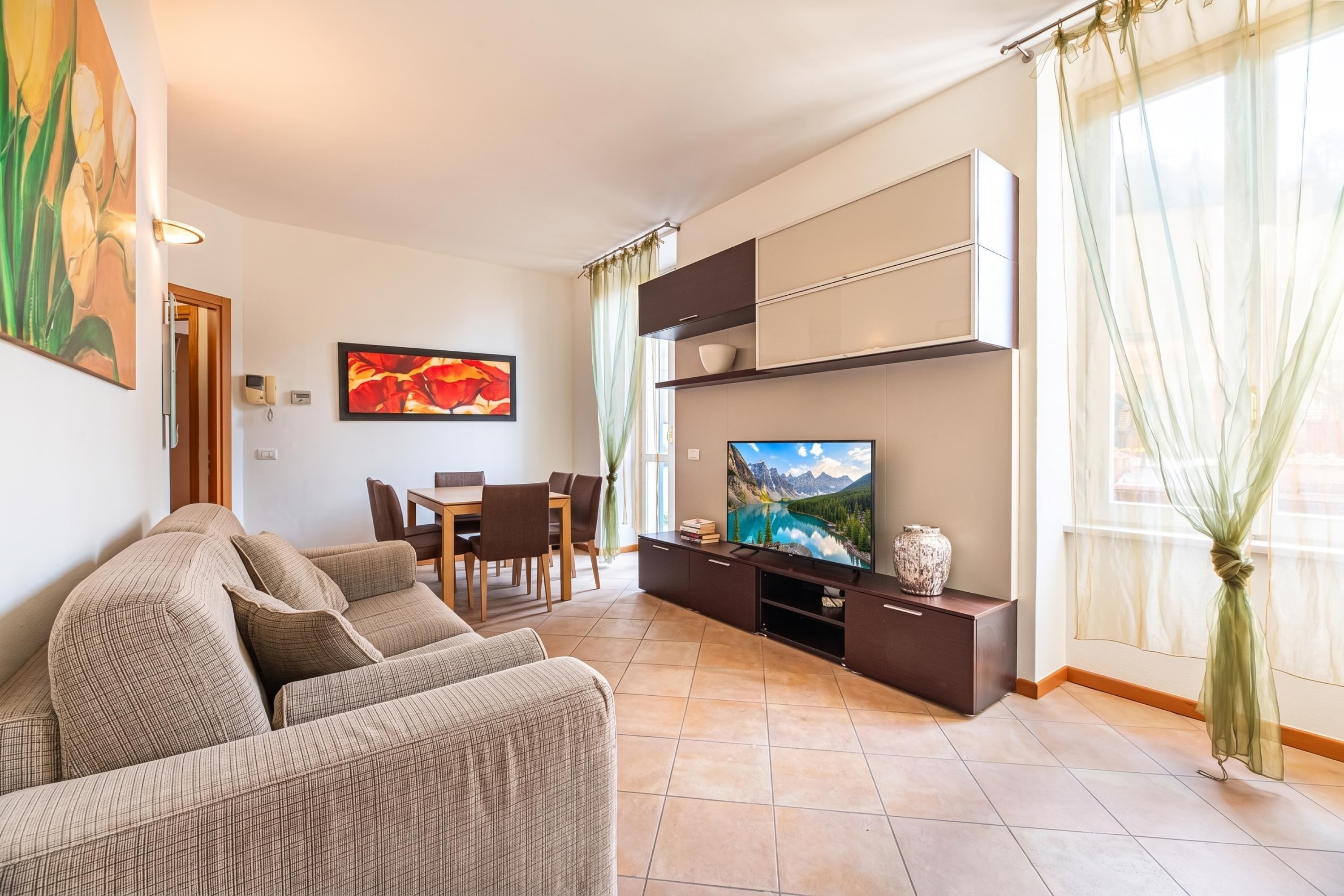 A living room with a sofa, TV, dining table, and chairs.