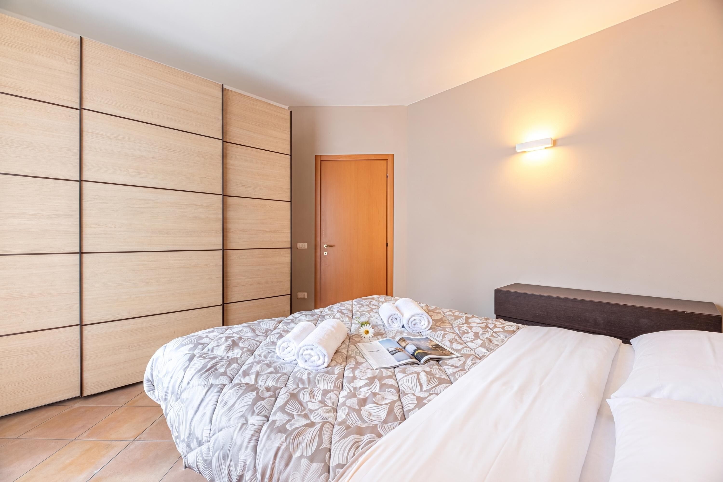 Habitación de hotel con cama, armario, puerta y lámpara fijada a la pared.