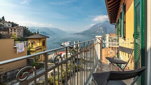 A balcony with a view of a lake and mountains, a chair, and a railing. - Varenna Lake View 2 (Varenna)