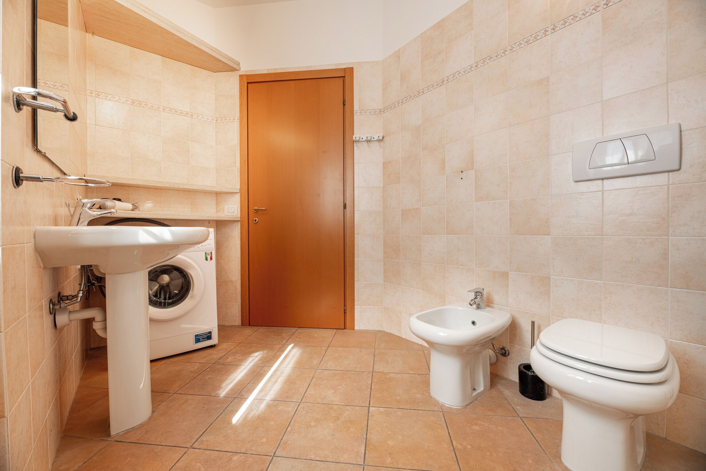 Un baño con lavadora, bidé, inodoro y lavamanos.
