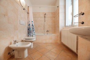 A bathroom with a bathtub, a bidet, a toilet, and a large sink.