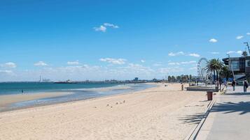 A wide sandy beach with a clear blue sky and a few clouds.