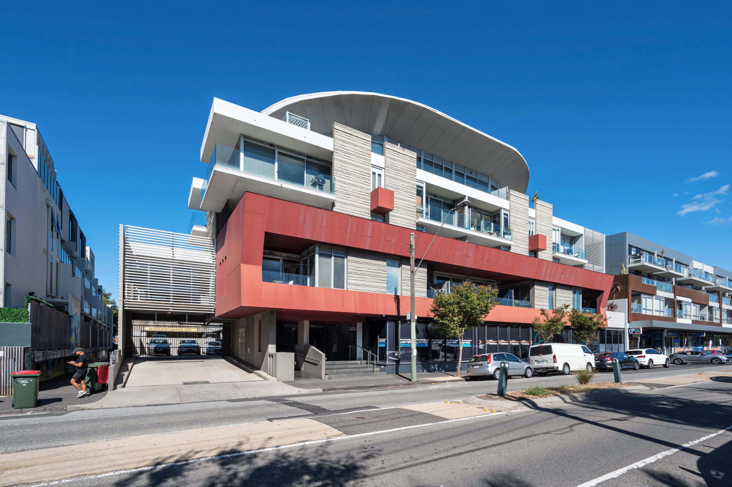 A modern multi-story building with a curved facade, large windows, and a flat roof.