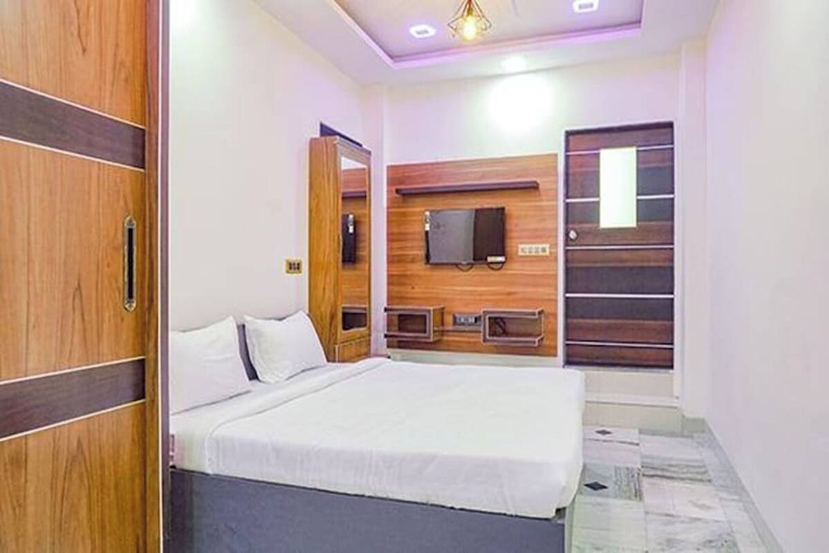 A bedroom with a bed, wooden headboard, a flat-screen TV, and a wardrobe.