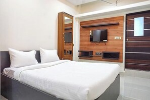 A modern bedroom with a bed, a TV mounted on the wall, and a wooden panel design. - Hotel Classic Square (Pune)