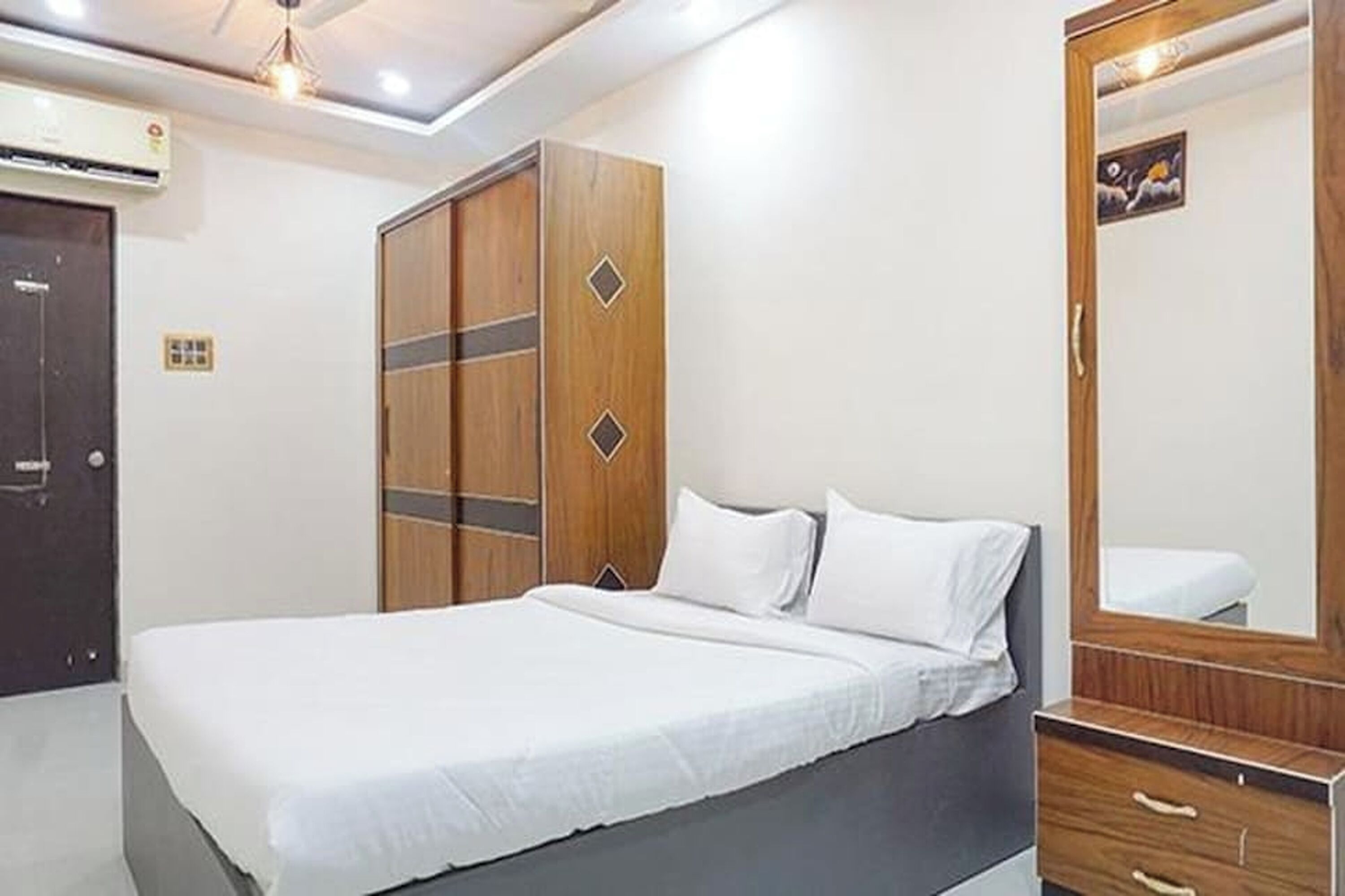 A bedroom with a bed, a wardrobe, a mirror, and a ceiling light.