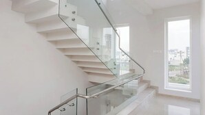 Una escalera moderna con barandillas de vidrio y pasamanos de metal, que sube a un nivel superior.