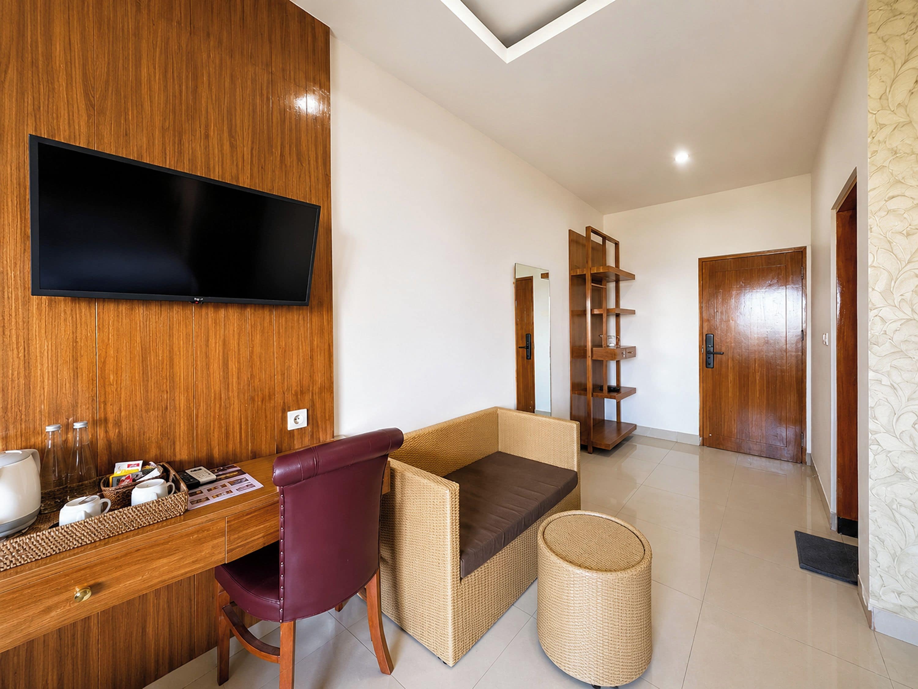 Un salon moderne avec un mur en bois, un téléviseur à écran plat, un bureau avec une chaise, un canapé en osier, une bibliothèque et une porte.