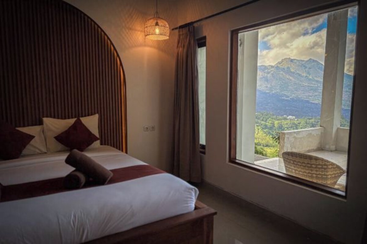 A bedroom with a large window offering a mountain view.