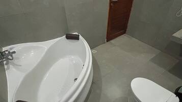 Un baño con bañera, inodoro y puerta de madera.
