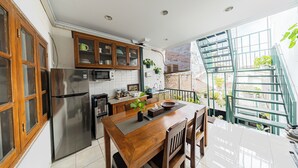 A kitchen with a refrigerator, wooden cabinets, and a dining table with chairs. - Omah Gerjen 29 (Yogyakarta)
