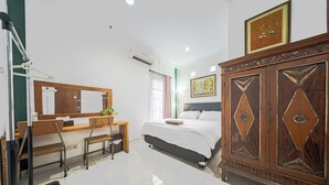 A bedroom with a bed, a desk with a chair, a large wooden cabinet, and a mirror. - Omah Gerjen 29 (Yogyakarta)