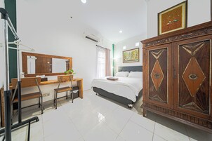 Un dormitorio con cama, un escritorio con silla, un armario grande de madera y un espejo.