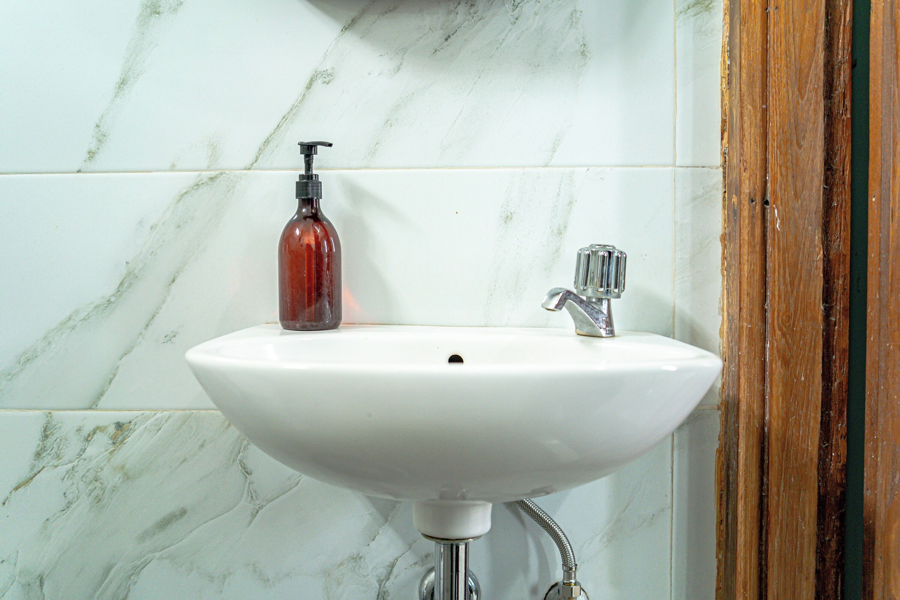 A bathroom with a white sink, a soap dispenser, and a faucet.