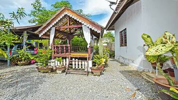 A gazebo with a wooden roof and white trim, surrounded by potted plants and a gravel ground.
