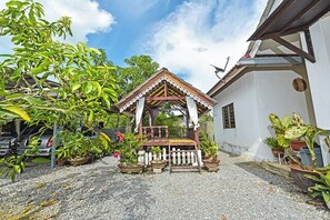 A gazebo with a wooden roof and white picket fence, surrounded by potted plants and a gravel ground. - Homestay Masha Padang Besar (Padang Besar)