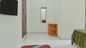 Un dormitorio con cama, un aparador de madera, un espejo y televisor instalado en la pared.