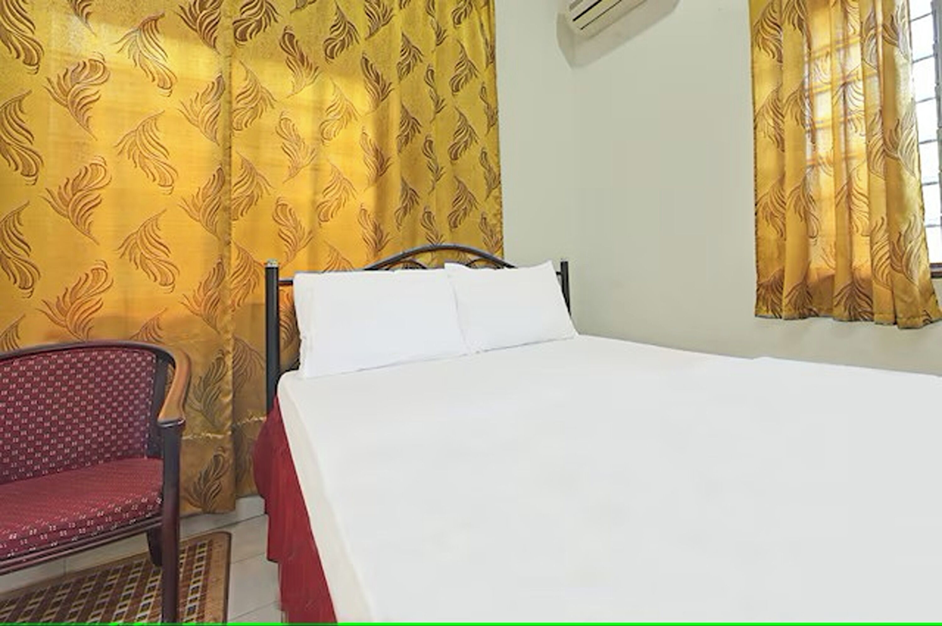 A room with a bed, a chair, and curtains.