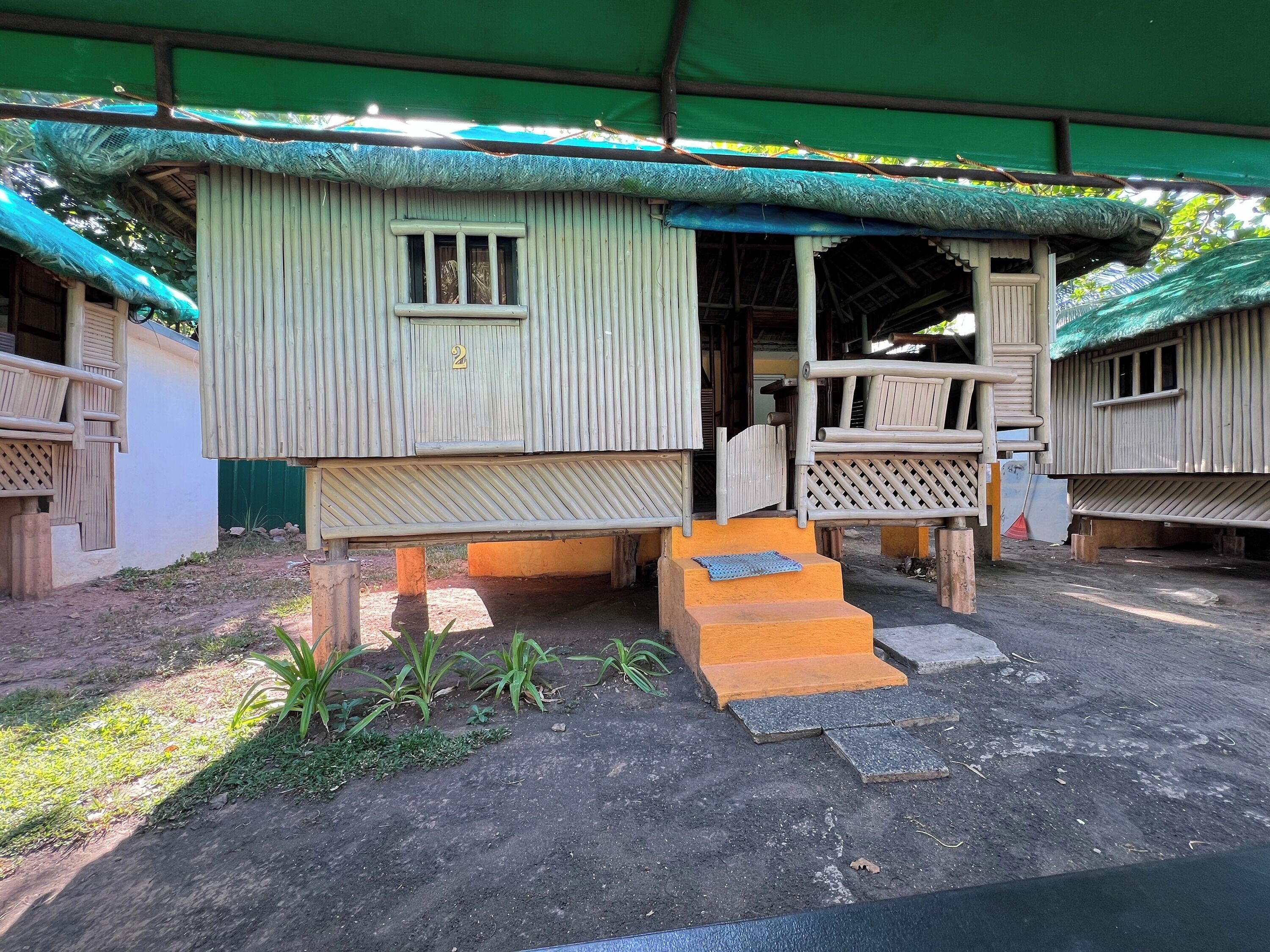 A rustic wooden building with a porch and a small staircase leading to a door marked with the number 2.