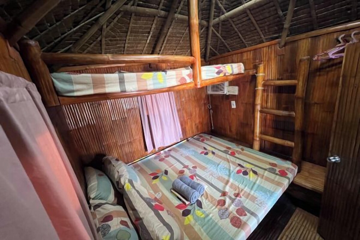 A small, cozy room with a bunk bed, wooden walls, and a simple bed with a floral bedspread.