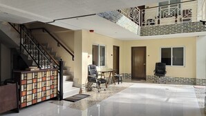 A spacious living area with a staircase, a dining table, and two chairs. - Elicon Suites Resort Bohol near City Center (Baclayon)