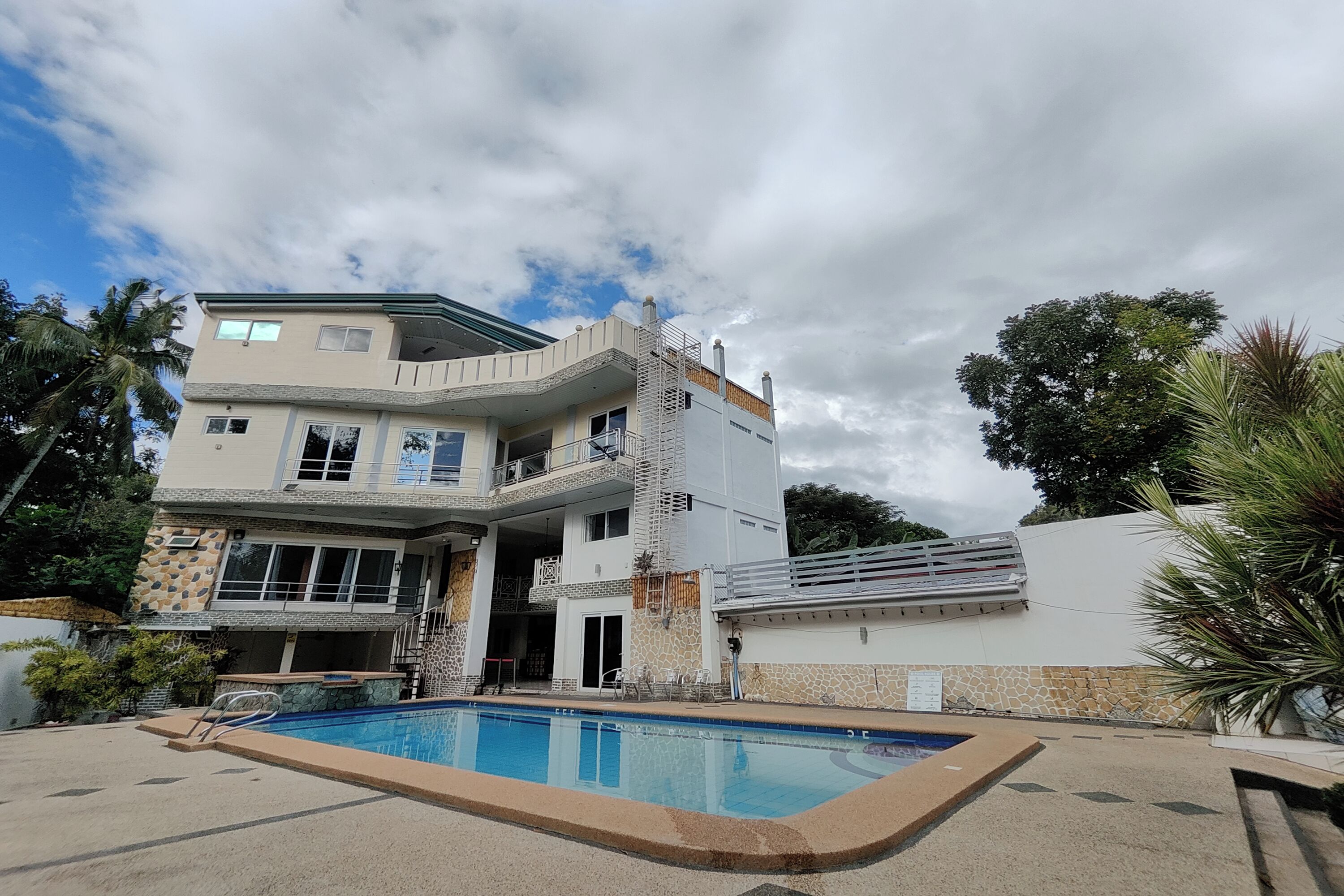 A two-story house with a swimming pool in front.