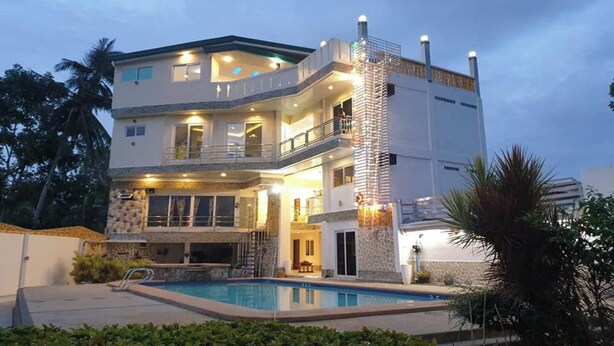 A multi-story house with a swimming pool, balconies, and a stone facade. - Elicon Suites Resort Bohol near City Center (Baclayon)