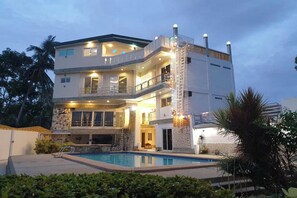 Una casa a più piani con piscina, balconi e facciata in pietra.