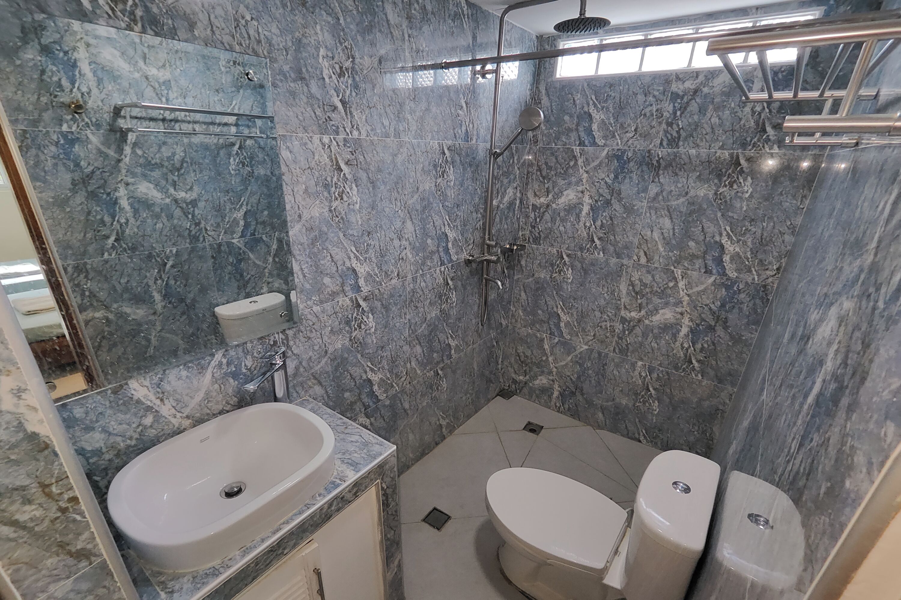 A bathroom with a marble sink, a toilet, and a shower.