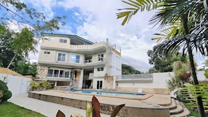 A multi-story house with a swimming pool, surrounded by greenery and a well-maintained lawn. - Elicon Suites Resort Bohol near City Center (Baclayon)