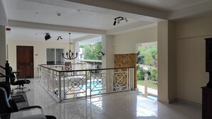 A spacious indoor area with a pool view, a reception desk, and a seating area with chairs. - Elicon Suites Resort Bohol near City Center (Baclayon)