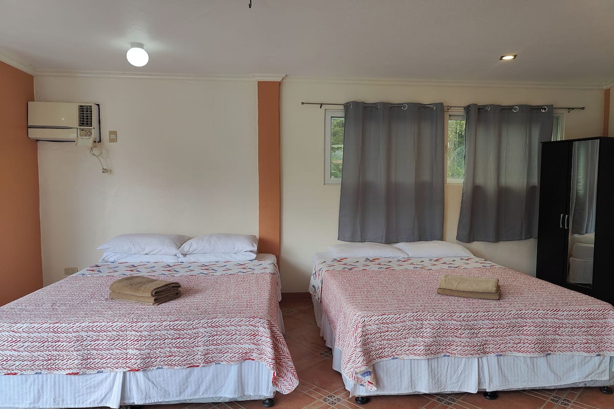 Una habitación con dos camas, un armario y aire acondicionado.