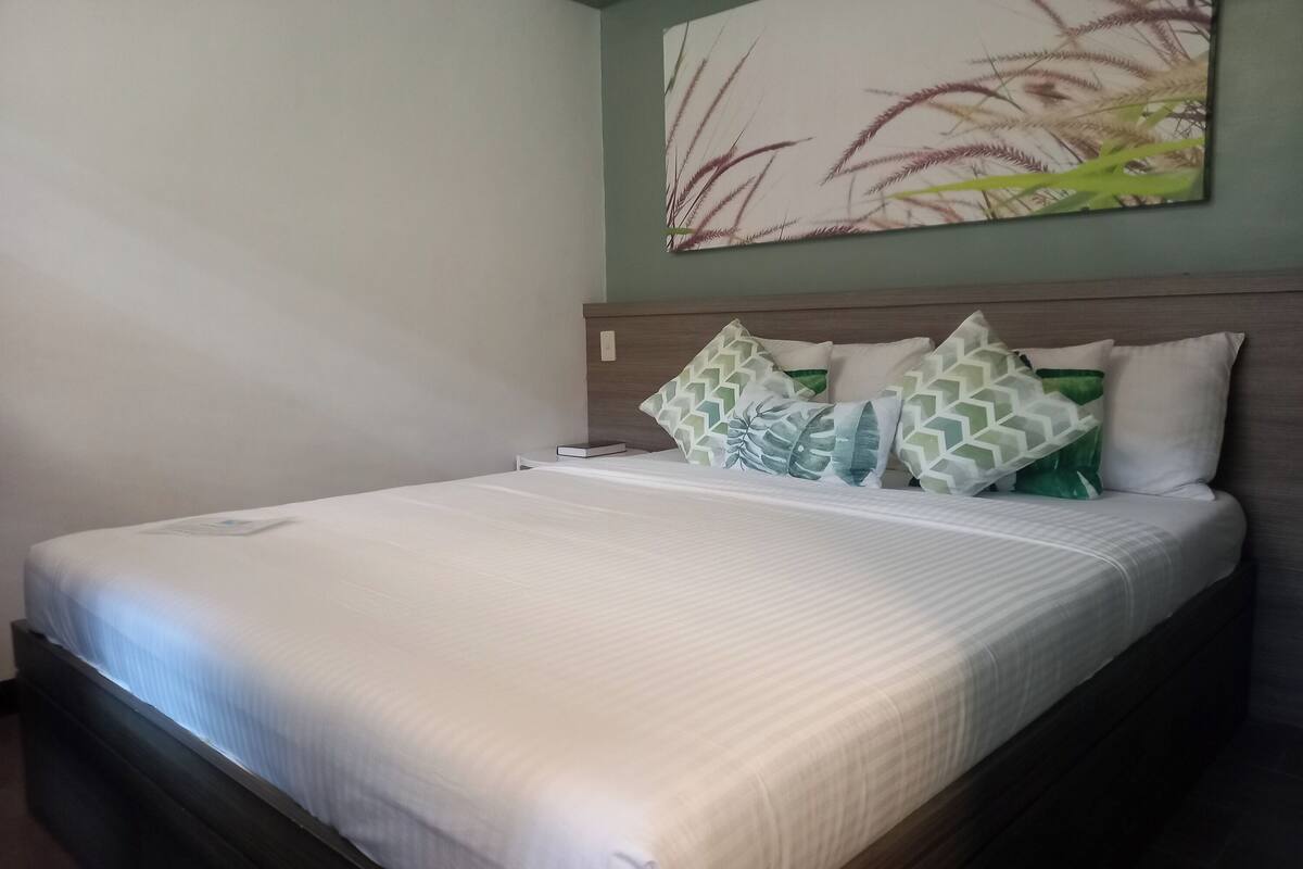 A neatly made bed with a white bedspread and multiple pillows, including patterned ones.