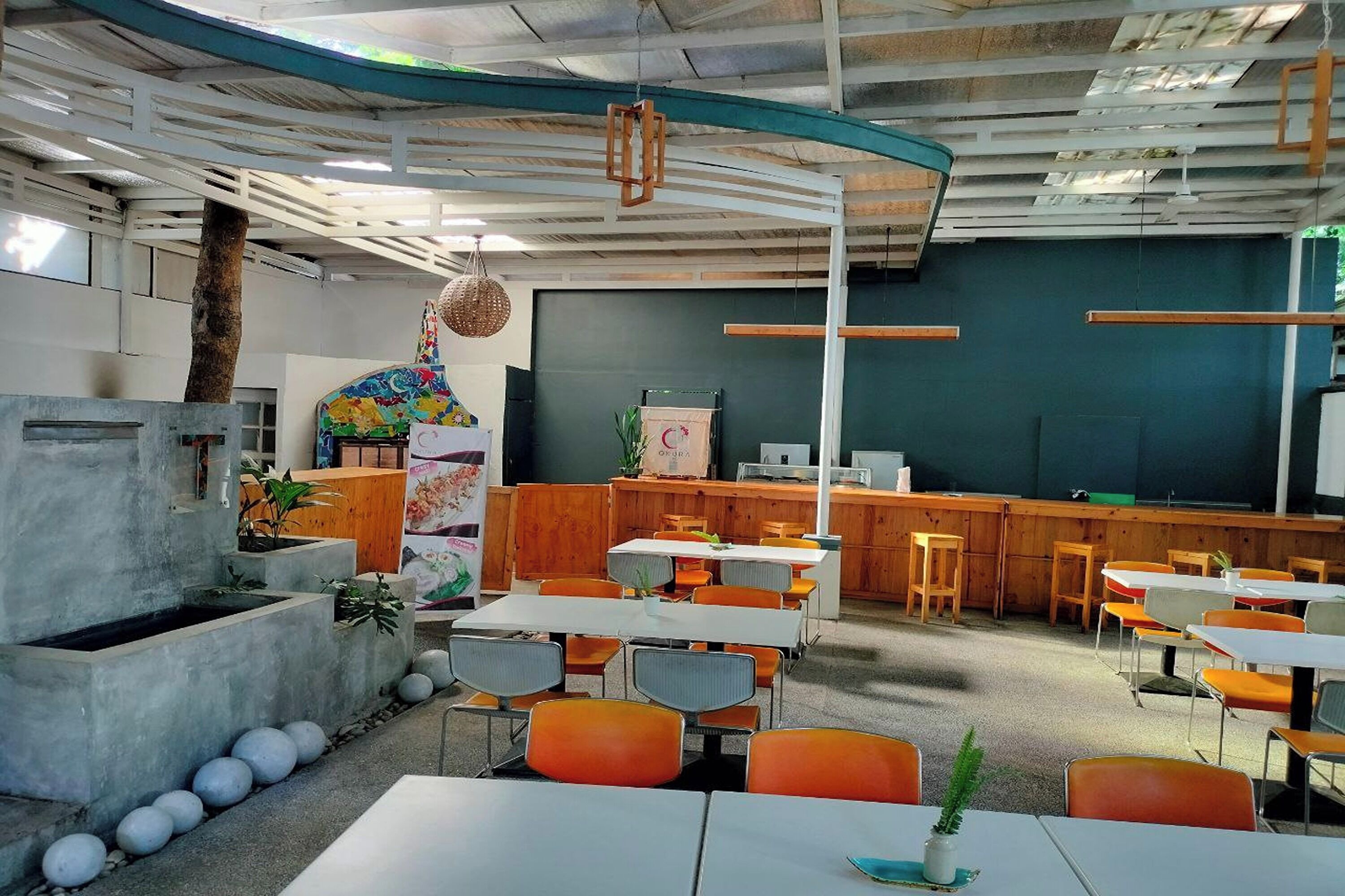 A modern indoor space with tables and chairs, a counter, and a chalkboard wall.