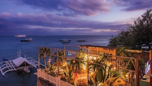 A waterfront restaurant with a view of the sea, outdoor seating, and a thatched-roof structure. - The Mark Resort (Lapu-Lapu)