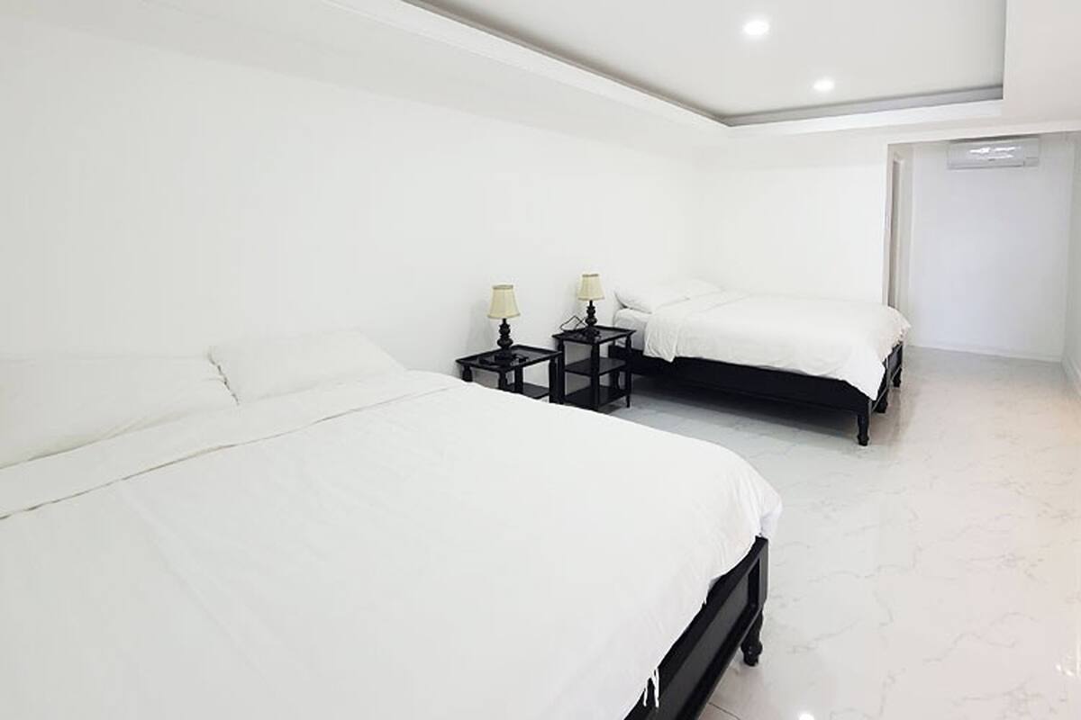 A modern hotel room with two beds, white bedding, and black nightstands with lamps.