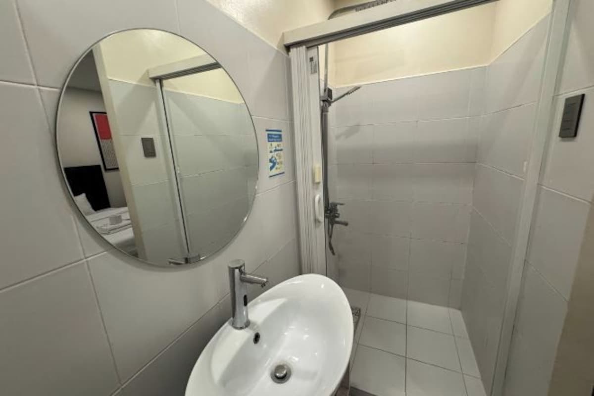 A bathroom with a white sink, a mirror, and a shower stall.